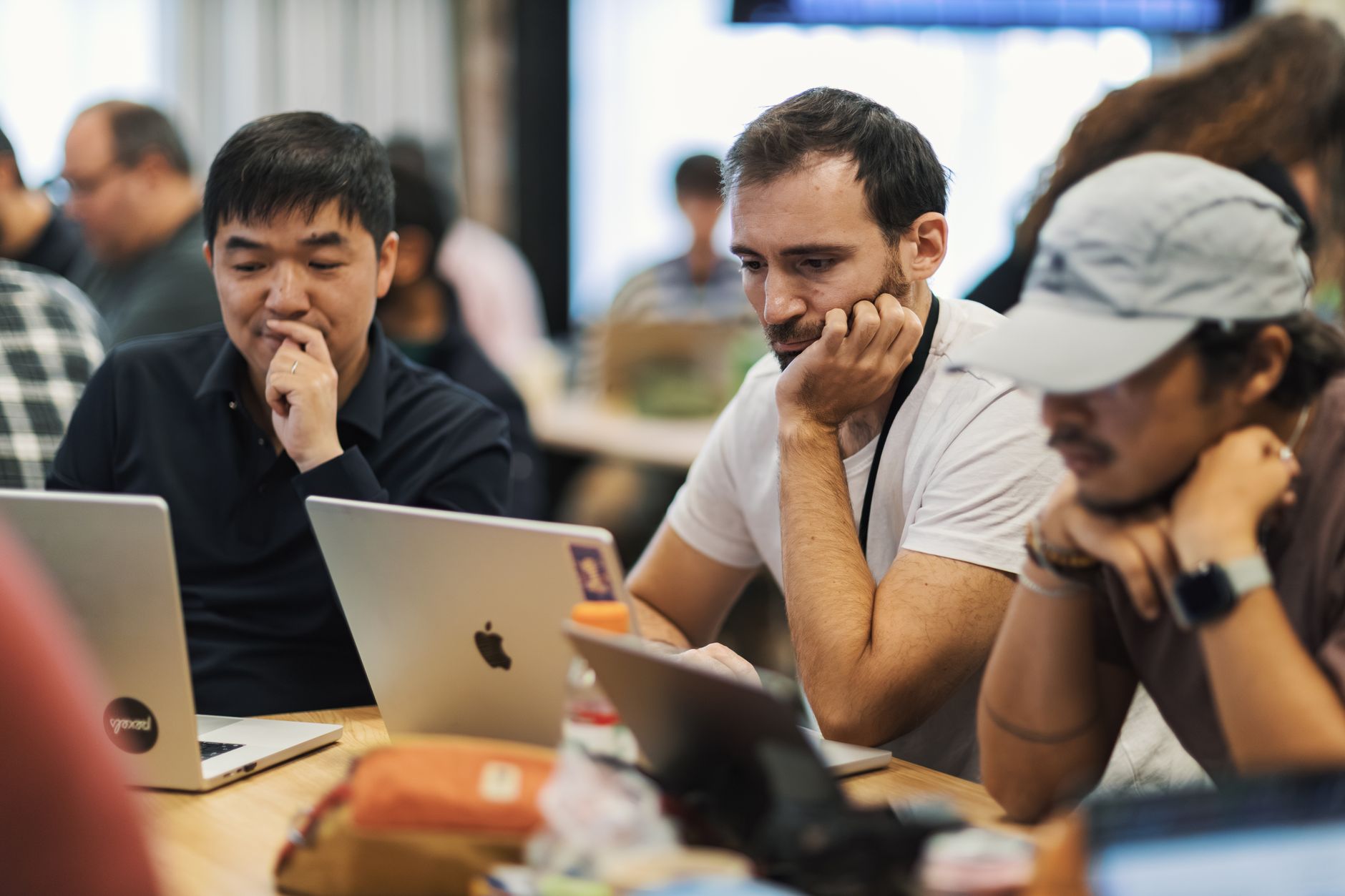 A diverse group of thinkers collaborating over a laptop, sharing ideas and sketches in a bright workspace.